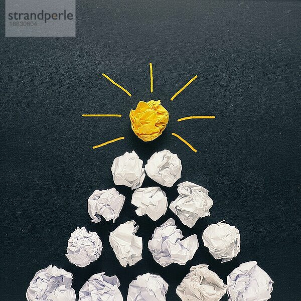 Pyramide aus weißem zerknittertem Papier mit einer gelben als Glühbirne Symbol  neue Idee Konzept Hintergrund