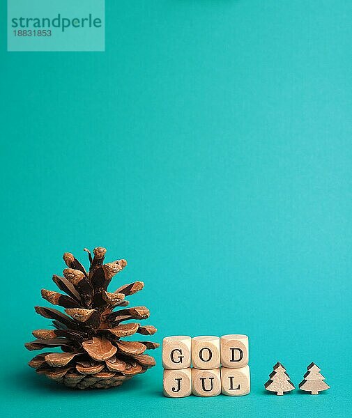 Kleine Holzblöcke mit der Aufschrift God Jul  skandinavische Frohe Weihnachten  türkisfarbener Hintergrund  minimalistische hölzerne Weihnachtsdekoration