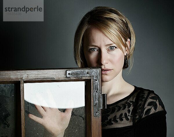 Portrait einer blonden Frau mit altem Fensterrahmen