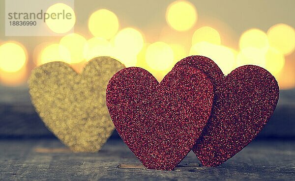 Drei glitzernde Herzformen mit verschwommenen Lichtern  Liebe oder Valentinstag Konzept Hintergrund