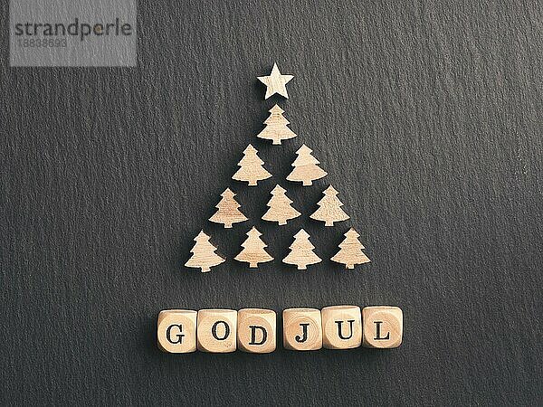 God Jul  skandinavische Frohe Weihnachten auf kleinen Holzwürfeln mit einer abstrakten Weihnachtsbaumform auf dunklem Schiefer