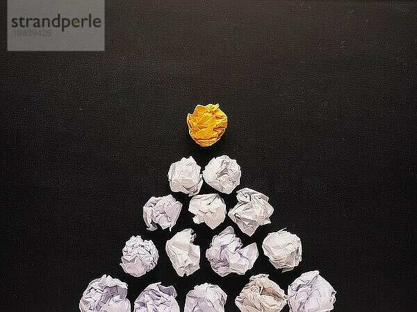 Pyramide aus weißem zerknittertem Papier mit einer gelben als Glühbirne Symbol  neue Idee Konzept Hintergrund
