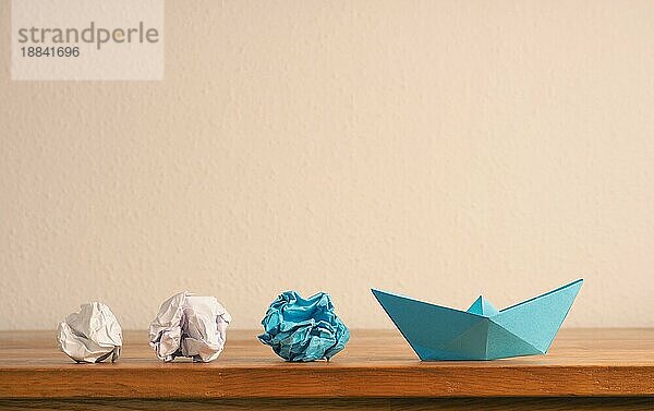 Teamwork Geschäftskonzept mit zerknittertem Papier und einem Papierboot auf einem hölzernen Bürotisch mit Platz für Text