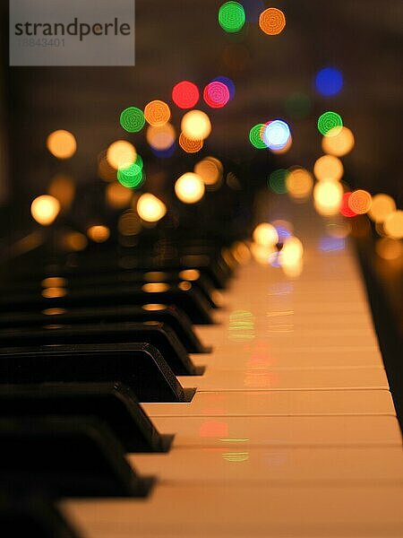 Piano Keyboard mit Lichterketten und bunte verschwommene Weihnachtsbeleuchtung  saisonale Hintergrund