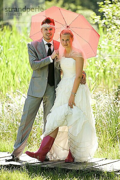 braut und bräutigam mit regenschirm und gummistiefel