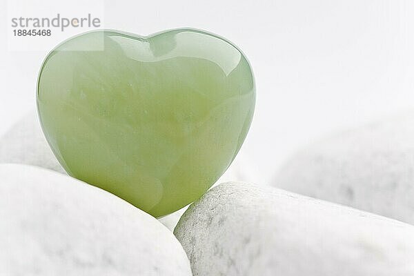 grünes quarz mineral herz als symbol der liebe auf weißen steinen