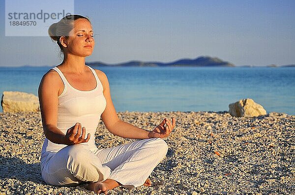 Junge Frau bei der YogaMeditation am Strand