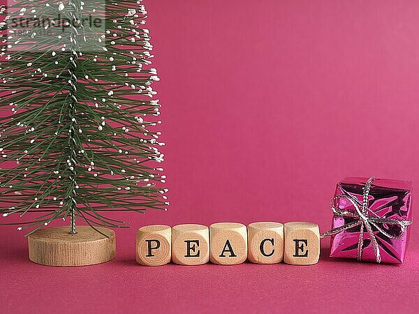 Kleine Holzblöcke mit der Aufschrift Frieden  Frohe Weihnachten  lila Hintergrund  minimalistische hölzerne Weihnachtsdekoration