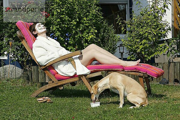 Frau auf Liegestuhl mit Mischlingshund