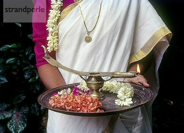 Ein Mädchen hält eine Öllampe und Blumen auf einem Tablett während des Onam-Festes  Kerala  Südindien  Indien  Asien