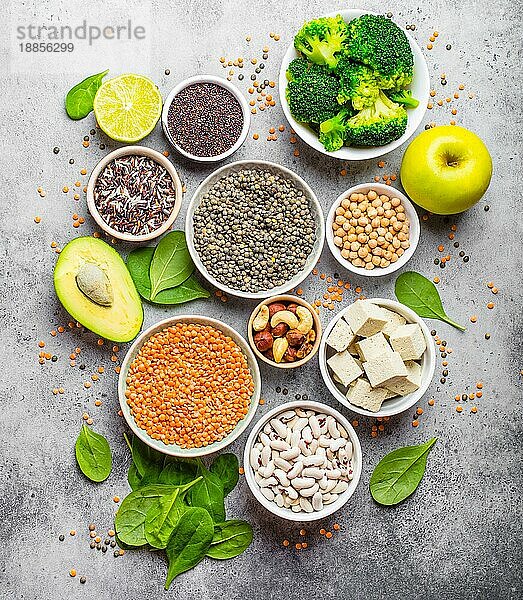 Vielfalt an nährstoffreichen Lebensmitteln für Veganer: Bohnen  Linsen  Quinoa  Tofu  Gemüse  Nüsse  Kichererbsen  Reis  Avocado  Obst  Stein rustikaler Hintergrund  Draufsicht. Gesunde ausgewogene vegetarische Ernährung