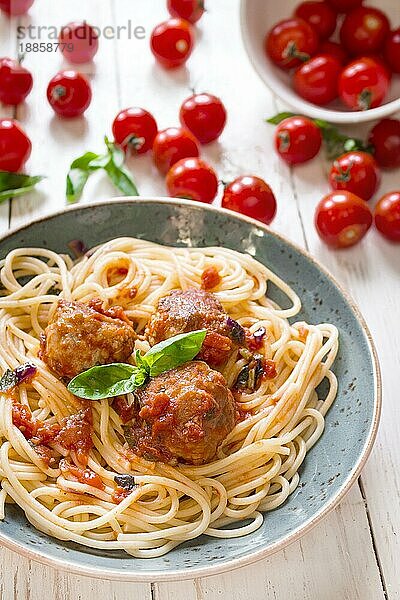 Nahaufnahme von leckeren Spaghetti mit Fleischbällchen und Tomatensauce auf einem Teller. Serviert auf einem weißen  rustikalen Holztisch. Ein italienisch-amerikanisches Gericht. Selektiver Fokus