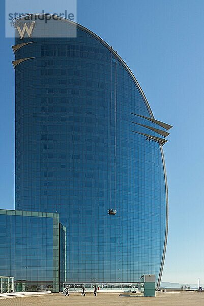 Arbeiter oder Fensterputzer auf einer Schaukelbühne im W Barcelona Hotel in Barceloneta. Das Gebäude hat eine halbmondförmige Silhouette mit 29 Stockwerken und ist ein neues Wahrzeichen Barcelonas Das riesige W Barcelona Hotel direkt am Meer im Stadtteil Barceloneta Barcelona