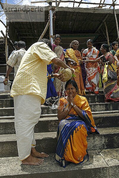 Der Ehemann gießt das Wasser aus dem Bronzetopf auf den Kopf seiner Frau  um für ein Kind während des Vinayak Chaturthi Ganesh Chaturthi Festes im Sri Karpaga Vinayakar Tempel in Pillaiyarpatti in der Nähe von Karaikudi  Tamil Nadu  Südindien  Indien  Asien zu beten  Asien