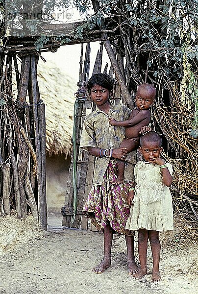 Ein Stammesmädchen mit ihren beiden Schwestern  von denen eine in der Nähe steht und die andere sich an ihrer Hüfte festhält  Tamil Nadu  Südindien  Indien  Asien