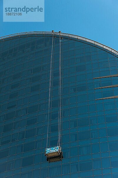 Arbeiter oder Fensterputzer auf einer Drehbühne im W Barcelona Hotel in Barceloneta. Das Gebäude hat eine halbmondförmige Silhouette mit 29 Stockwerken und ist ein neues Wahrzeichen von Barcelona