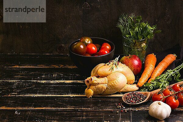 Rohes ganzes Huhn bereit zum Kochen. Huhn  Gemüse  Kräuter  Gewürze auf schwarzem  rustikalem Holzhintergrund. Platz für Text. Rahmen für Lebensmittel. Diät oder gesunde Ernährung. Zutaten zum Kochen. Selektiver Fokus