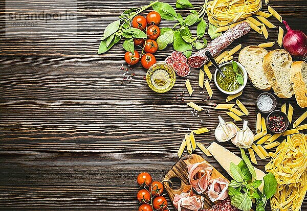 Draufsicht auf italienische traditionelle Lebensmittel  Vorspeisen und Snacks wie Salami  Prosciutto  Käse  Pesto  Ciabatta  Olivenöl  Pasta auf rustikalem Holzhintergrund mit Platz für Text in der Mitte