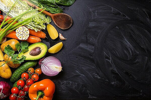 Gemüse  Kräuter  rohe Zutaten zum Kochen und Holzlöffel auf rustikalen schwarzen Kreidetafel Hintergrund. Gesundes  sauberes Essen Konzept. Vegane oder glutenfreie Ernährung. Platz für Text. Ansicht von oben. Salat machen