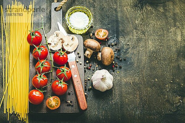 Kirschtomaten  Champignons  Spaghetti  Holzbrett  Messer. Knoblauch  Olivenöl. Kochender Hintergrund. Platz für Text. Zutaten zum Kochen. Kochendes Abendessen. Selektiver Fokus. Lebensmittel-Hintergrund