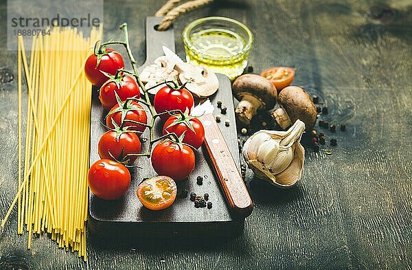 Kirschtomaten  Champignons  Spaghetti  Holzbrett  Messer. Knoblauch  Olivenöl. Konzept des Kochens. Platz für Text. Zutaten zum Kochen. Abendessen kochen. Selektiver Fokus. Essen zubereiten