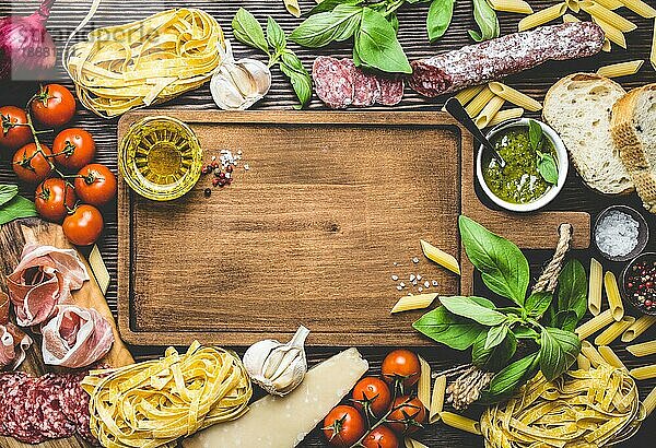 Draufsicht auf italienische traditionelle Lebensmittel  Vorspeisen und Snacks wie Salami  Prosciutto  Käse  Pesto  Ciabatta  Olivenöl  Pasta auf rustikalem Holzbrett mit Platz für Text und Retro-Stil
