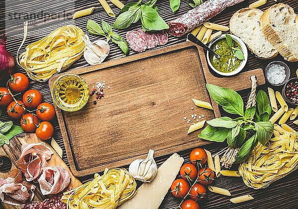 Draufsicht auf italienische traditionelle Lebensmittel  Vorspeisen und Snacks wie Salami  Prosciutto  Käse  Pesto  Ciabatta  Olivenöl  Pasta auf rustikalen Holzbrett mit Platz für Text und Retro-Stil