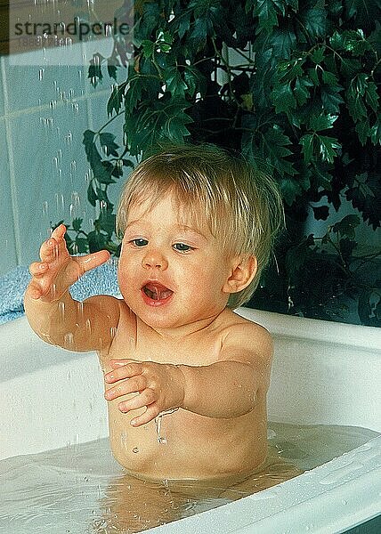 BABY SPIELT MIT WASSER IN EINER BADEWANNE