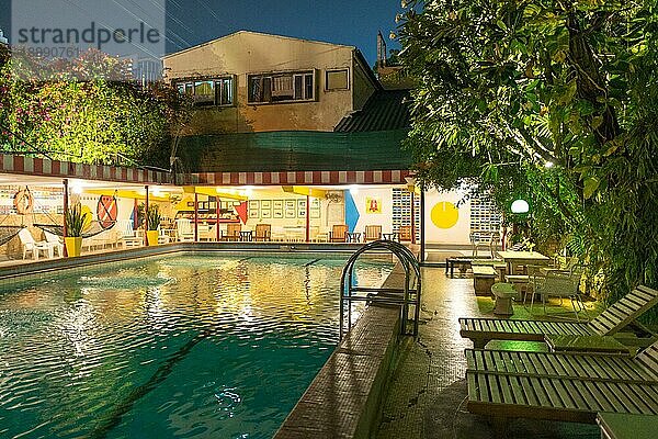 Hotelpool im Freien im Garten eines Hotels mit tropischer Vegetation mitten in Bangkok bei Nacht