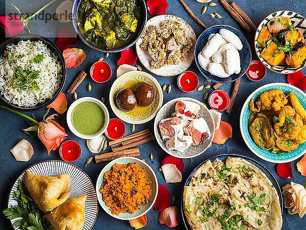 Festliches Essen für das indische Fest Diwali. Naan  Samosa  Reis  Paneer  Süßigkeiten Holiday indischen Tisch mit Essen  Süßigkeiten  Blumen  brennende Kerzen. Diwali-Feier Abendessen. Verschiedene indische Gerichte  Snacks