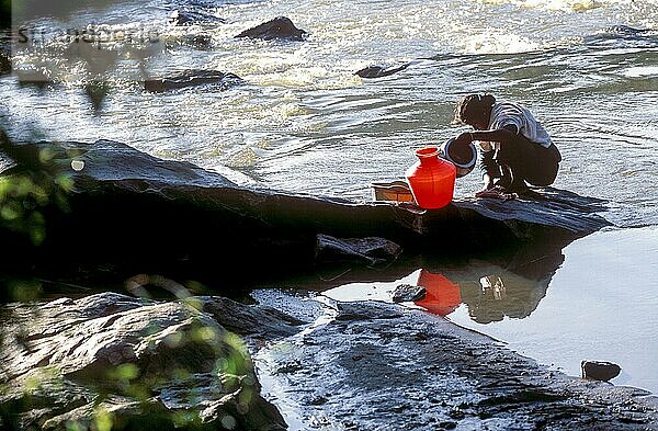 Ein Stammesmädchen wäscht Utensilien am Moyar-Fluss im Mudumalai-Nationalpark  Nilgiris  Tamil Nadu  Südindien  Indien  Asien