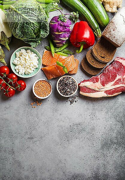 Draufsicht auf ein Sortiment gesunder  ausgewogener Lebensmittel: Fleisch  Fisch  Gemüse  Brot  Getreide  Bohnen  Hintergrund aus Stein  Platz für Text. Rohe Zutaten für das Kochen gesunder Mahlzeit  gut für Diät  sauberes Essen