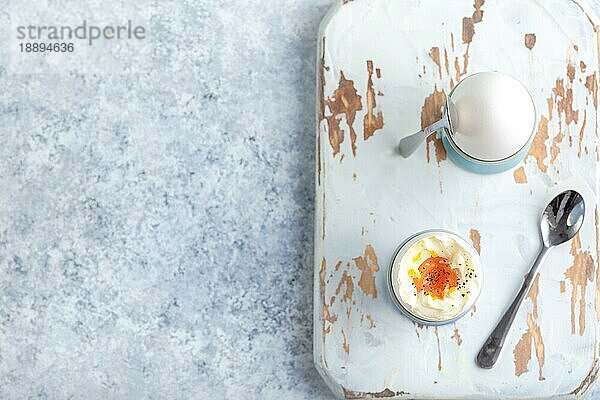 Frische weich gekochte Eier in Ständern  Löffel  Holzkochbrett  weißer Beton rustikalen Hintergrund. Ansicht von oben. Weiche Eier  gesundes Frühstück. Platz für Text. Selektiver Fokus. Eiweiß-Fitness-Frühstück