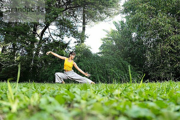 Frau beim Üben von Tai Chi Chuan im Freien. Tai Chi Praktiken können dazu beitragen  die Flexibilität  die Kraft und das Gleichgewicht des Körpers zu verbessern sowie Stress und Ängste abzubauen