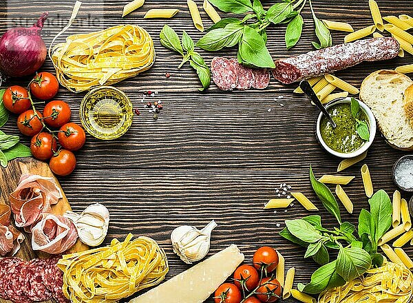 Draufsicht auf italienische traditionelle Lebensmittel  Vorspeisen und Snacks wie Salami  Prosciutto  Käse  Pesto  Ciabatta  Olivenöl  Pasta auf rustikalem Holzhintergrund mit Platz für Text in der Mitte