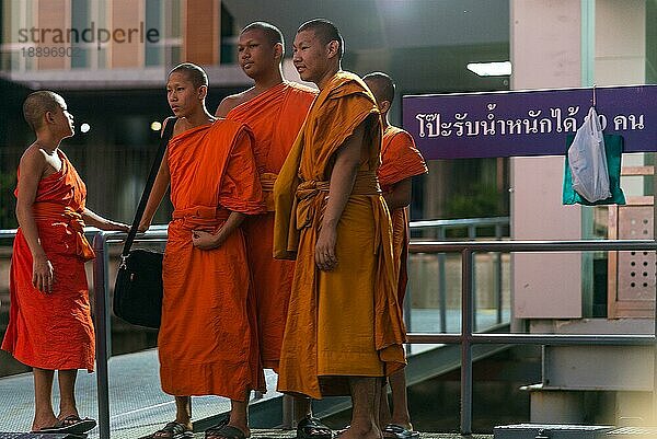 Buddhistische Mönche unterschiedlichen Alters  die auf einem Ponton auf dem Chao Phraya Fluss in Bangkok auf das Expressboot warten