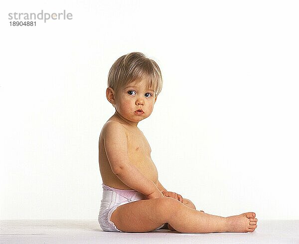 BABY MÄDCHEN SITZEND VOR WEISSEM HINTERGRUND