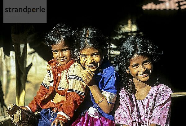 Drei Betta kurumba Stammeskinder posieren glücklich für die Kamera in Theppakadu im Mudumalai Nationalpark  Nilgiris  Tamil Nadu  Südindien  Indien  Asien