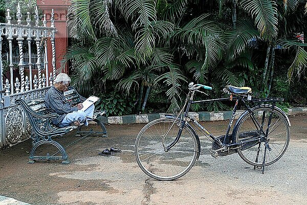 Ein alter Mann sitzt entspannt und schreibt im Lal Bagh Garten mit Fahrrad in Bengaluru Bangalore  Karnataka  Südindien  Indien  Asien