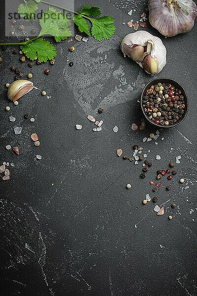 Nahaufnahme von traditionellen Kochzutaten: Knoblauch  Olivenöl  Salz  Pfeffer  frische Kräuter auf dunklem  rustikalem Hintergrund. Lebensmittelrahmen  Konzept für das Kochen gesunder Lebensmittel mit Platz für Text  Ansicht von oben
