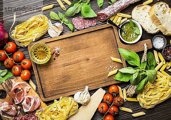 Draufsicht auf italienische traditionelle Lebensmittel  Vorspeisen und Snacks wie Salami  Prosciutto  Käse  Pesto  Ciabatta  Olivenöl  Pasta auf rustikalen Holzbrett mit Platz für Text und Retro-Stil