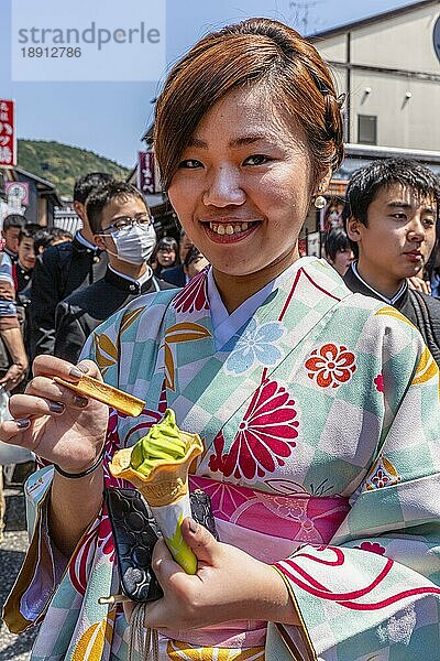Kyoto Japan. Lächelnde Frau im traditionellen Kimono  die ein Eis ißt