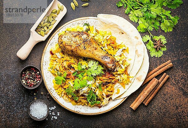 Eine Draufsicht auf Biryani-Hühnchen mit Basmatireis  Gemüse  Koriander und Naan-Brot in einer Schüssel  ein traditionelles indisches Gewürzgericht  auf rustikalem Steinhintergrund. Abendessen im indischen Stil