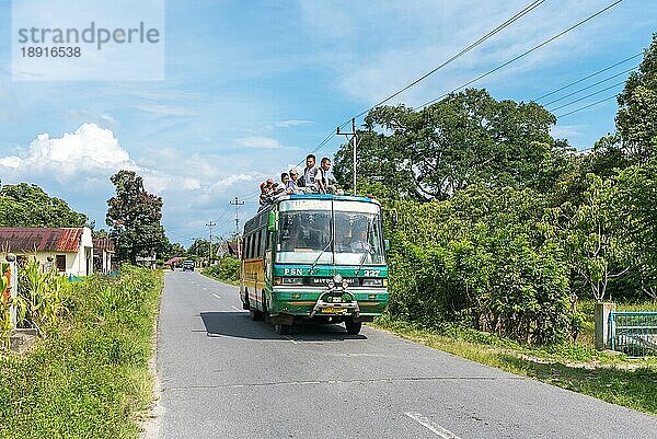 Transport von jungen Studenten  einige sitzen auf dem Dach des Busses  gesehen auf der Insel Samosir in der Provinz Nord Sumatra