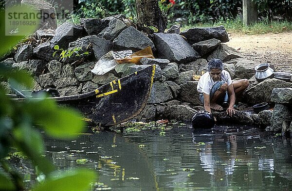 Eine alte Frau beim Reinigen von Küchenutensilien Backwaters von Kerala  Südindien  Indien  Asien