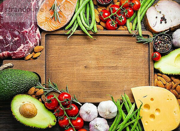 Holzschneidebrett und ketogene Low-Carb-Zutaten für gesunde Gewichtsabnahme Ernährung  Draufsicht  Kopie Raum. Keto-Lebensmittel: Fleisch  Fisch  Avocado  Käse  Gemüse  Nüsse Saubere Ernährung  gesunde Fette