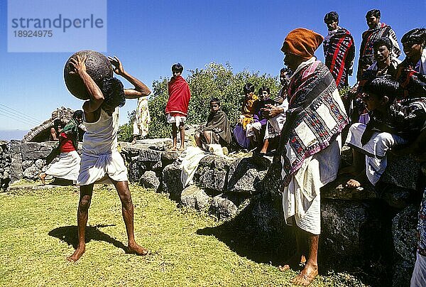 Toda's Youngman hebt mit Stolz und Freude einen großen kugelförmigen Stein und legt ihn für einige Zeit auf die Schulter in Kinnakorai  Nilgiris  Ooty Udhagamandalam  Tamil Nadu  Südindien  Indien  Asien