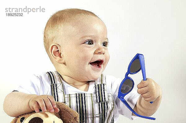 Lächelnder Baby-Junge mit Sonnenbrille vor weißem Hintergrund