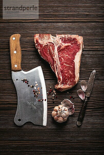 Draufsicht auf rohes frisches marmoriertes Fleisch Steak T-Bone  rustikales Fleischbeil  Gewürze auf hölzernem Hintergrund. Kochen saftige Bio-Steak Metzgerei Konzept  gesunde saubere Ernährung  Nahaufnahme