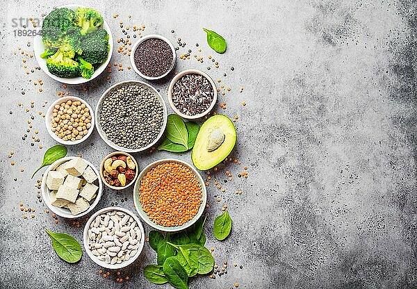 Vielfalt an nährstoffreichen Lebensmitteln für Veganer mit Kopierfläche: Bohnen  Linsen  Quinoa  Tofu  Gemüse  Nüsse  Kichererbsen  Reis  Avocado  Steinhintergrund  Draufsicht. Gesunde vegetarische Ernährung